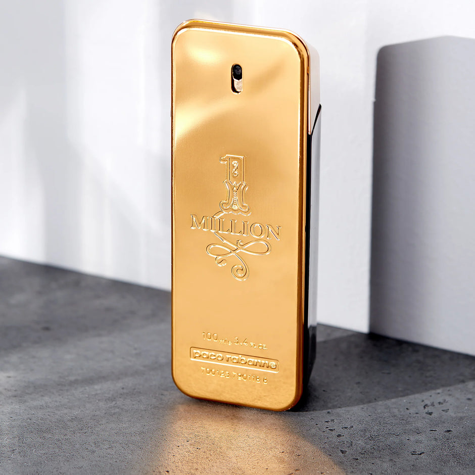 Gold bottle of Paco Rabanne 1 Million perfume on a gray surface with a white background. Perfume