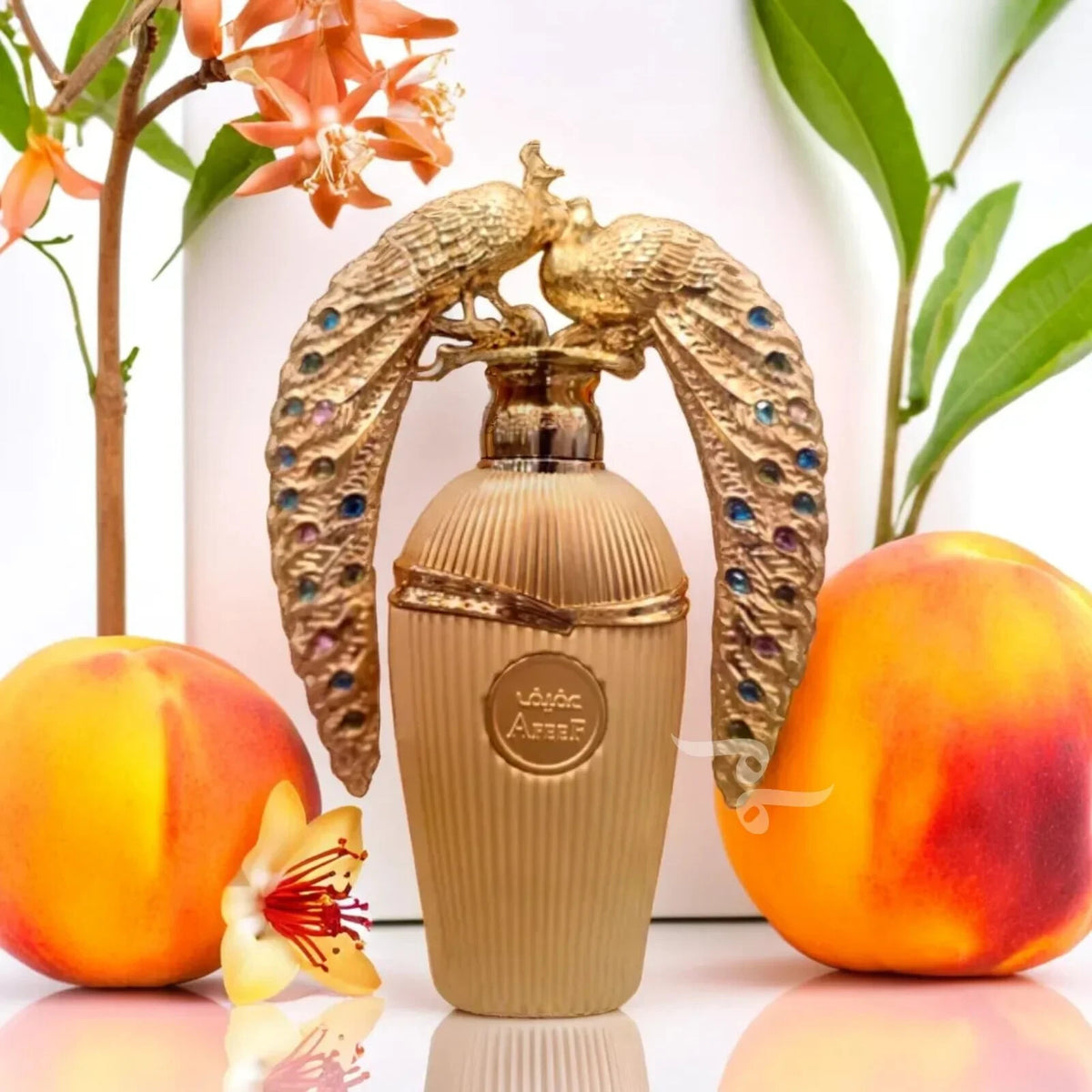 Gold perfume bottle with peacock design surrounded by peaches and flowers on a white background