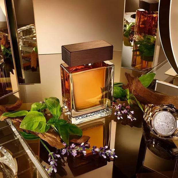 Dolce & Gabbana perfume bottle on a decorative surface with plants and a watch.