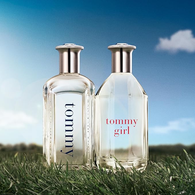Two Tommy Hilfiger perfume bottles on grass with a blue sky background