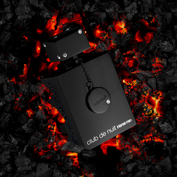 Black perfume bottle labeled 'club de nuit intense man' on a fiery background