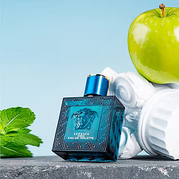 Versace Eau de Toilette bottle with a green apple and mint leaves on a light blue background