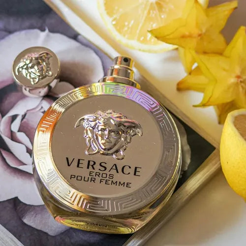 Versace Eros pour Femme perfume bottle with decorative elements on a textured surface