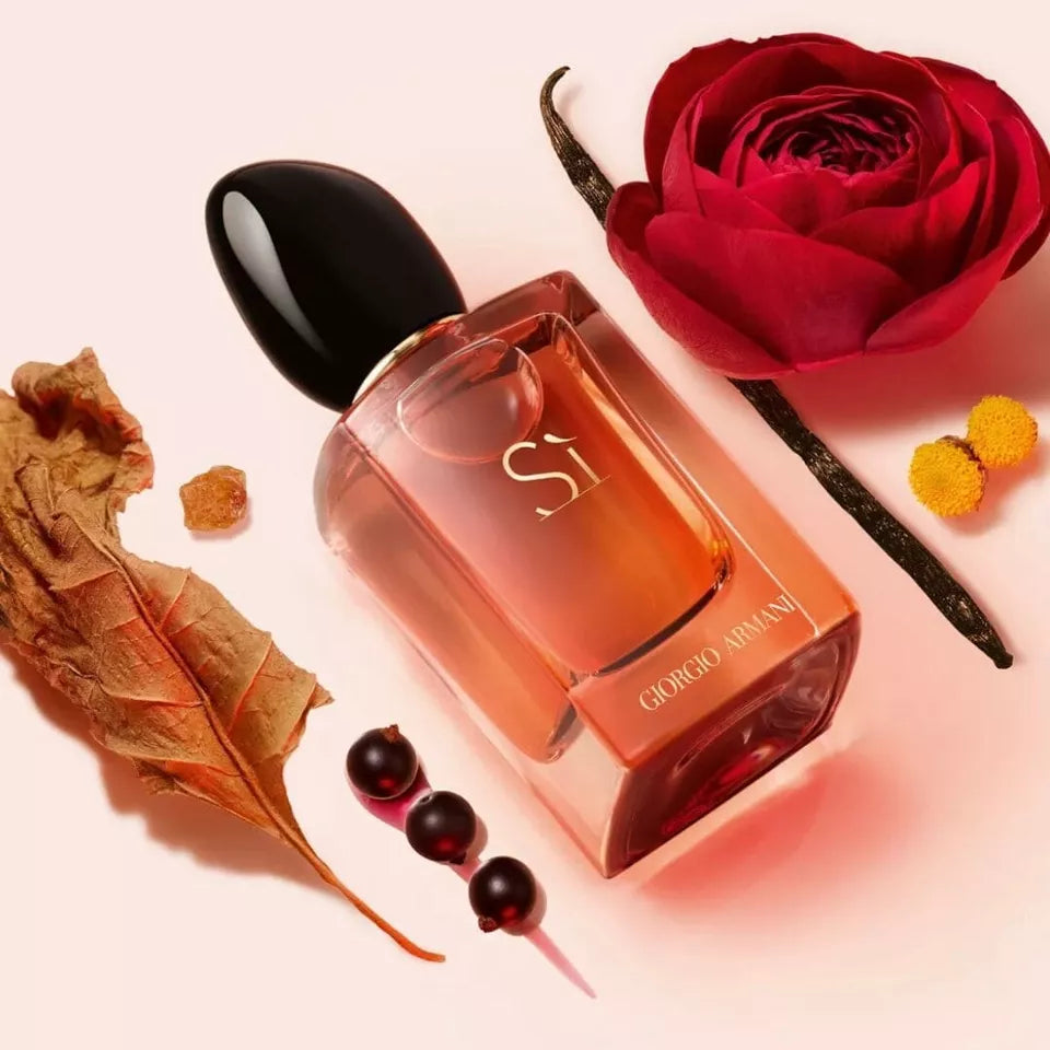 Perfume bottle with a red rose and dried leaves on a light pink background