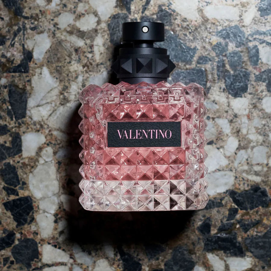 Valentino perfume bottle with pink diamond pattern on a textured stone background