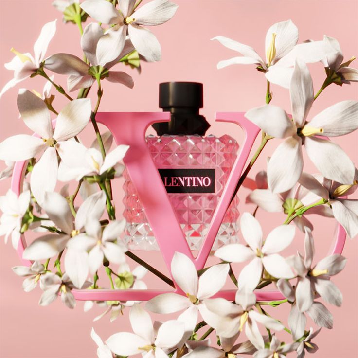 Pink Valentino perfume bottle surrounded by white flowers on a pink background