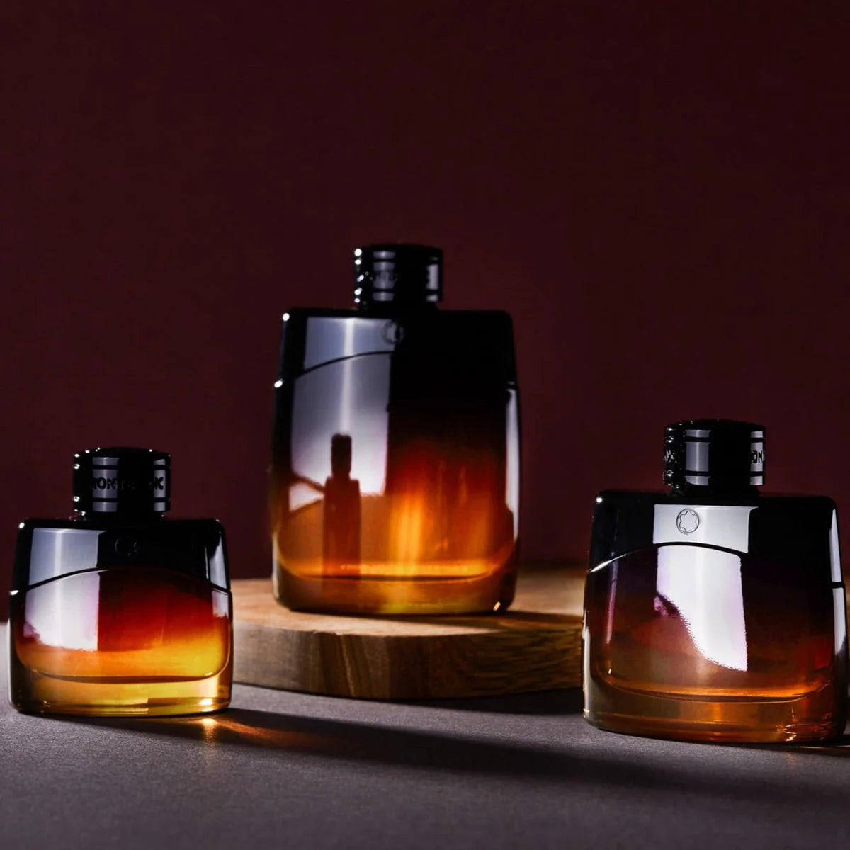 Three amber-colored perfume bottles with reflective surfaces on a dark background