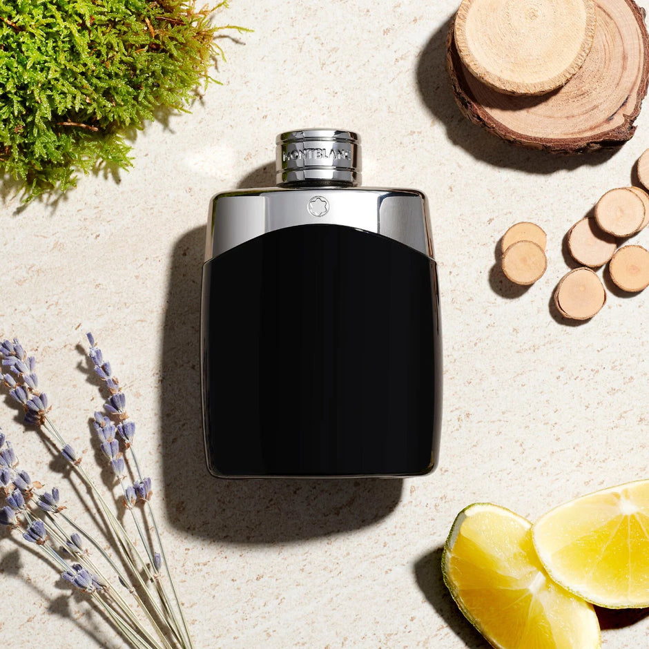Montblanc black perfume bottle on a textured surface with natural elements like lavender and lemon slices.