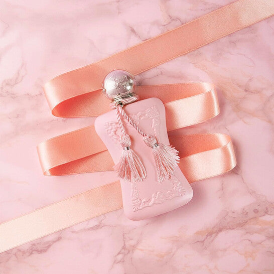 Pink perfume bottle with decorative elements on a pink marble background