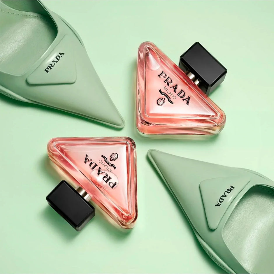 Prada shoes and triangular perfume bottles on a light green background