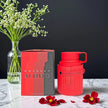 Red Odyssey Artisto mug with packaging and flowers on a dark background