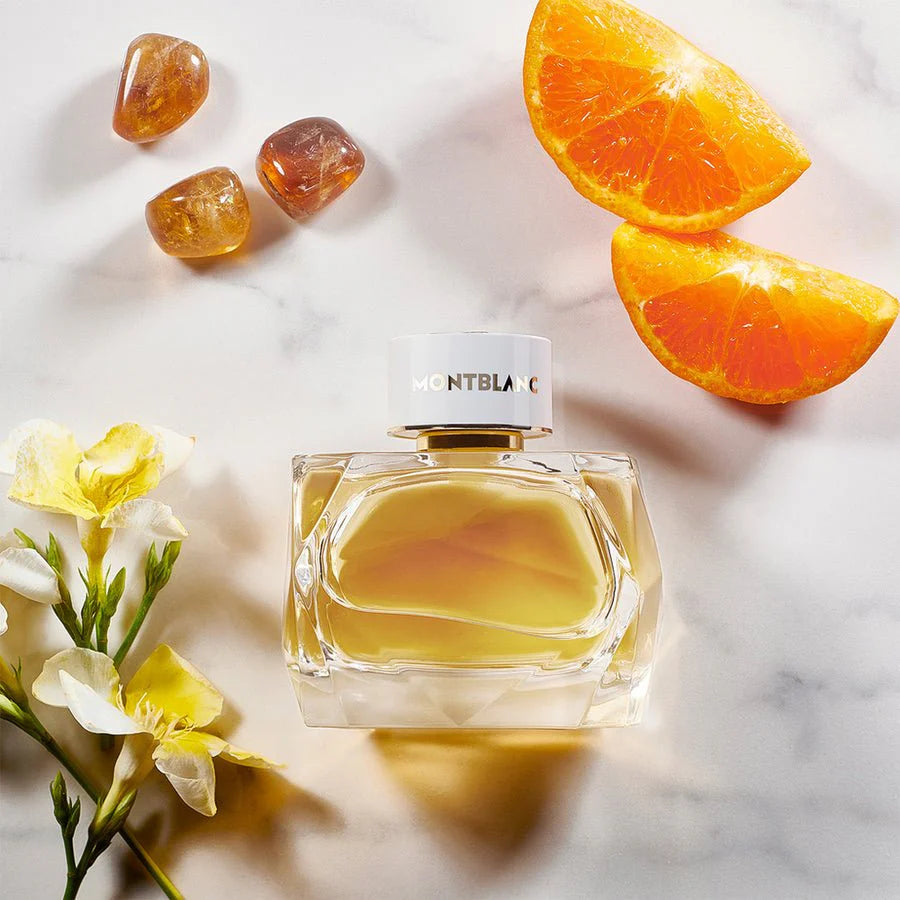 Montblanc perfume bottle with orange slices and flowers on a marble surface