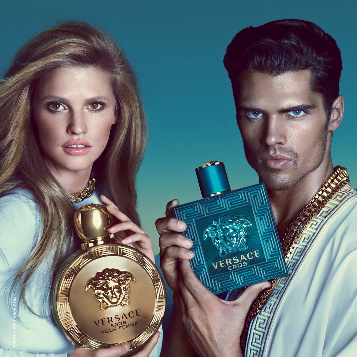 Two people holding Versace perfume bottles against a blue background